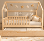 Cama casita Montessori evolutiva PALENCIA 105 x 190 cm en pino natural con el cajón cama extraído, vista frontal con barrera y guirnalda de estrellas