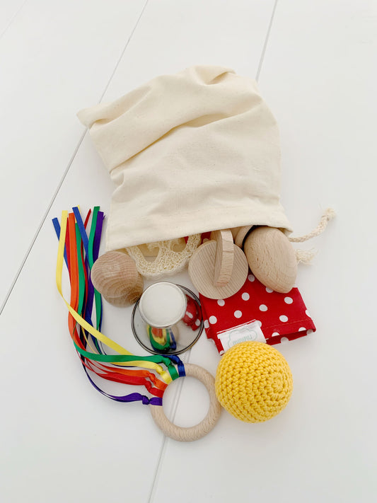 Baby treasure bag with wooden and fabric sensory objects, ideal for early development.