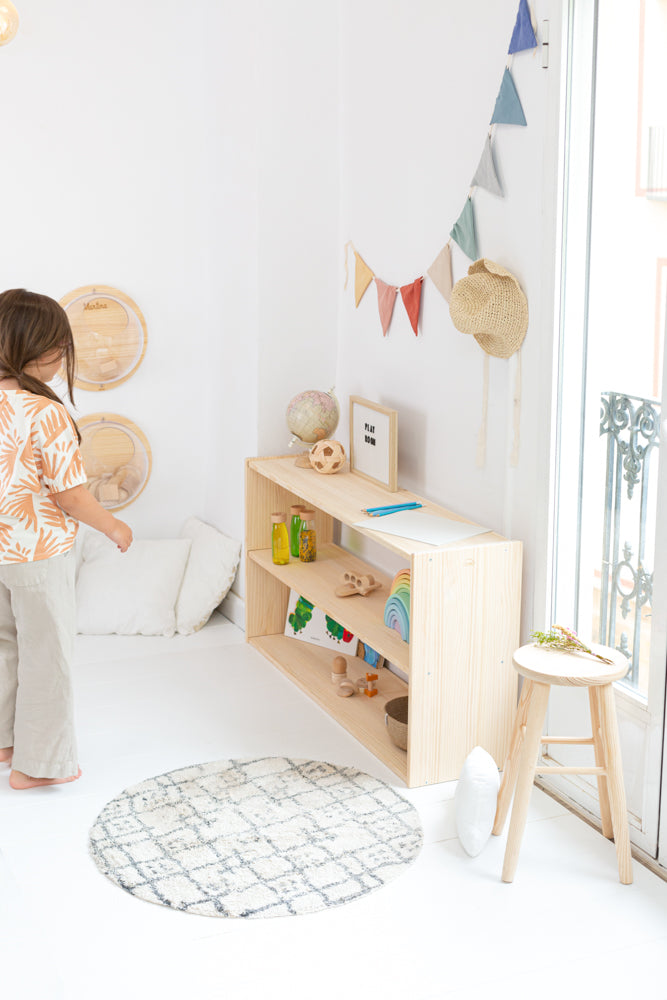 Estantería Montessori de madera maciza con tres estantes, vista lateral. Estantería con juguetes, guirnalda y más productos minipiu.